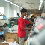 Trabalhadores operam máquinas em uma fábrica têxtil.