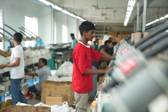 Trabalhadores operam máquinas em uma fábrica têxtil.