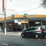 Posto de combustíveis Ipiranga movimentado, com veículos circulando em uma avenida urbana.