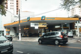 Posto de combustíveis Ipiranga movimentado, com veículos circulando em uma avenida urbana.