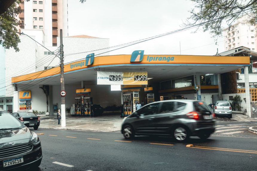 Posto de combustíveis Ipiranga movimentado, com veículos circulando em uma avenida urbana.
