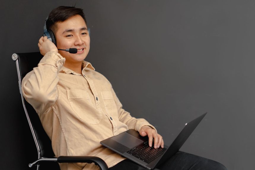 Agente de atendimento sorrindo, usando headset e laptop em ambiente interno