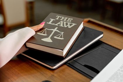Livro sobre direito e balança da justiça sobre uma mesa de madeira.
